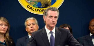 Man in suit at podium with microphones during press conference