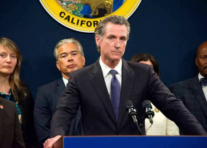 shutterstock_2259638251 Man in suit at podium with microphones during press conference