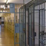 Paperwork Tricks Bury Political Prisoners Prison corridor with barred doors