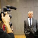 Robert F. Kennedy Jr. speaks with a reporter while being filmed indoors