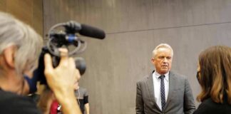 Robert F. Kennedy Jr. speaks with a reporter while being filmed indoors