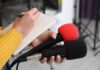2028 Sparks: AOC Rejoins DSA Journalist holding two microphones while writing in a notebook