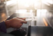 Hand holding a passport and boarding pass at an airport counter