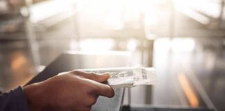Hand holding a passport and boarding pass at an airport counter