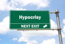 Green highway sign reading hypocrisy next exit