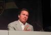 Arnold Schwarzenegger speaking at a podium with a microphone