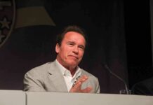 Arnold Schwarzenegger speaking at a podium with a microphone