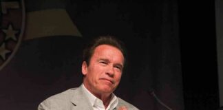 Arnold Schwarzenegger speaking at a podium with a microphone
