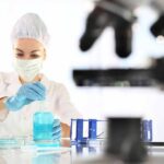 Lab-Grown Milk That Barely Touches A Cow Scientist in lab coat handling blue liquid