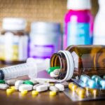 Medicine pills and syringe on table with brown bottle