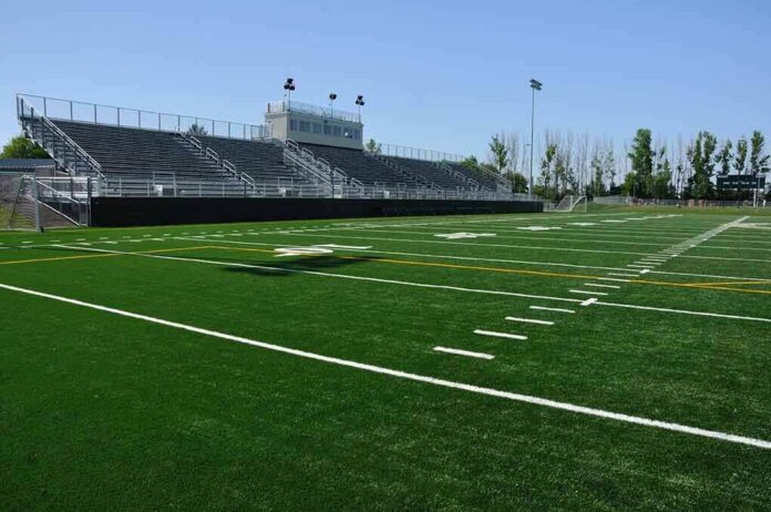 Empty football stadium with bleachers and artificial turf field