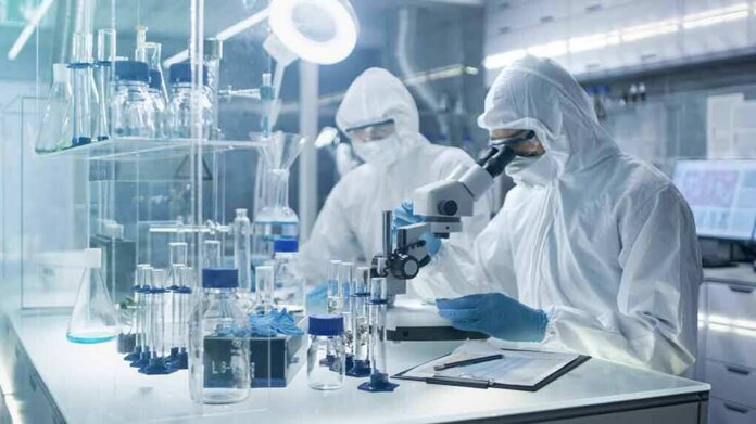 Scientists in protective suits using a microscope in a laboratory