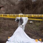 forensic investigator at outdoor crime scene behind caution tape
