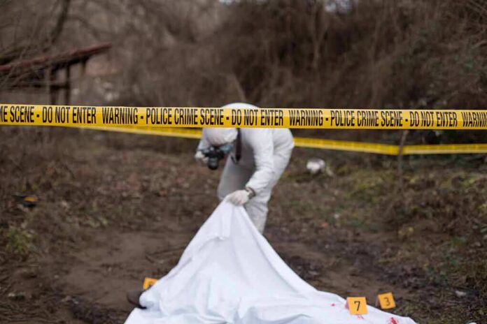 forensic investigator at outdoor crime scene behind caution tape