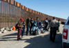 See What This Migrant CARAVAN Will Find at Our Border Group of people standing by a border fence with officers and vehicles