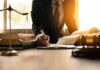Lawyer writing at desk with scales and gavel
