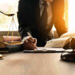 Lawyer writing at desk with scales and gavel