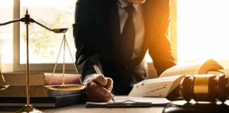 Lawyer writing at desk with scales and gavel