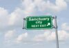 Democrat Accused of ‘Shrine to Cop KILLERS’ Green highway sign against cloudy sky