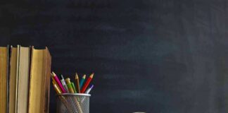 Books and pencils on a desk in front of a chalkboard