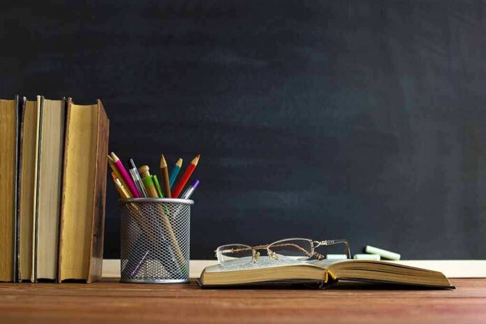 Books and pencils on a desk in front of a chalkboard
