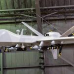 military drone with missiles suspended in a hangar