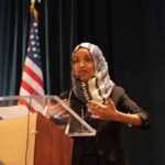 Ilhan Omar speaking at a podium with a microphone