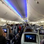 Airplane cabin with passengers seated and seatback screens