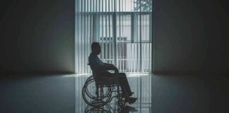 Person in a wheelchair silhouetted by a large window