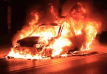 Car engulfed in flames on a dark road