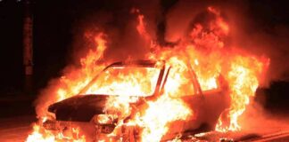 Car engulfed in flames on a dark road
