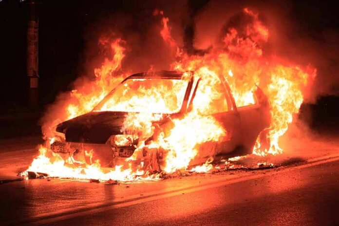 Car engulfed in flames on a dark road