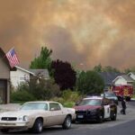 Emergency vehicles respond to wildfire near suburban homes