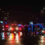 Nighttime police scene with flashing lights on a wet city street