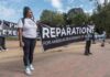 Protesters holding a large reparations banner outdoors
