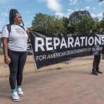 Protesters holding a large reparations banner outdoors
