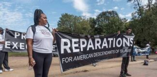 Protesters holding a large reparations banner outdoors