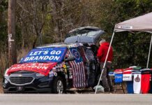 Street vendor with car covered in political banners selling T-shirts