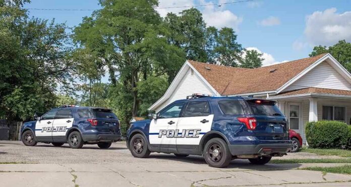 shutterstock_2195086633 Two police SUVs parked near a suburban house