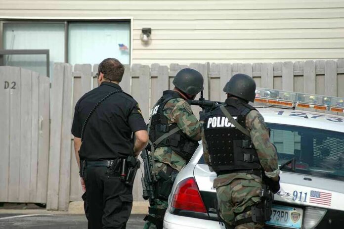 police officers in tactical gear beside patrol car